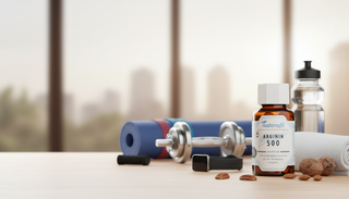 Ein Braunglas-Fläschchen naturafit Arginin 500 Nahrungsergänzungsmittel steht auf einem Holztisch, umgeben von Mandeln und Pekannüssen als natürlichen Quellen, sowie Sportzubehör wie einer Hantel, einer Yogamatte und einem Fitness-Tracker, vor einem Fenst